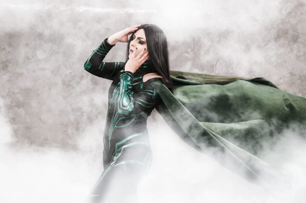 Cosplayer als Hela aus dem Marvel Cinematic Universum steht mit wehendem Mantel vor einem grauen Hintergrund im Nebel